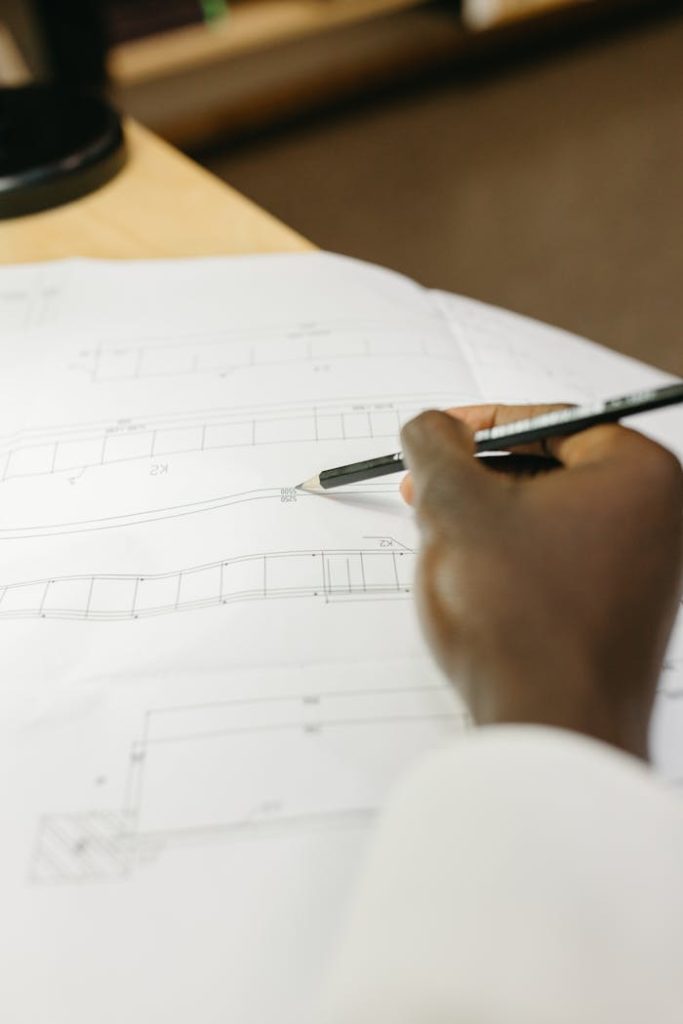 Detailed view of an architects hand drafting a blueprint in a workspace setting.