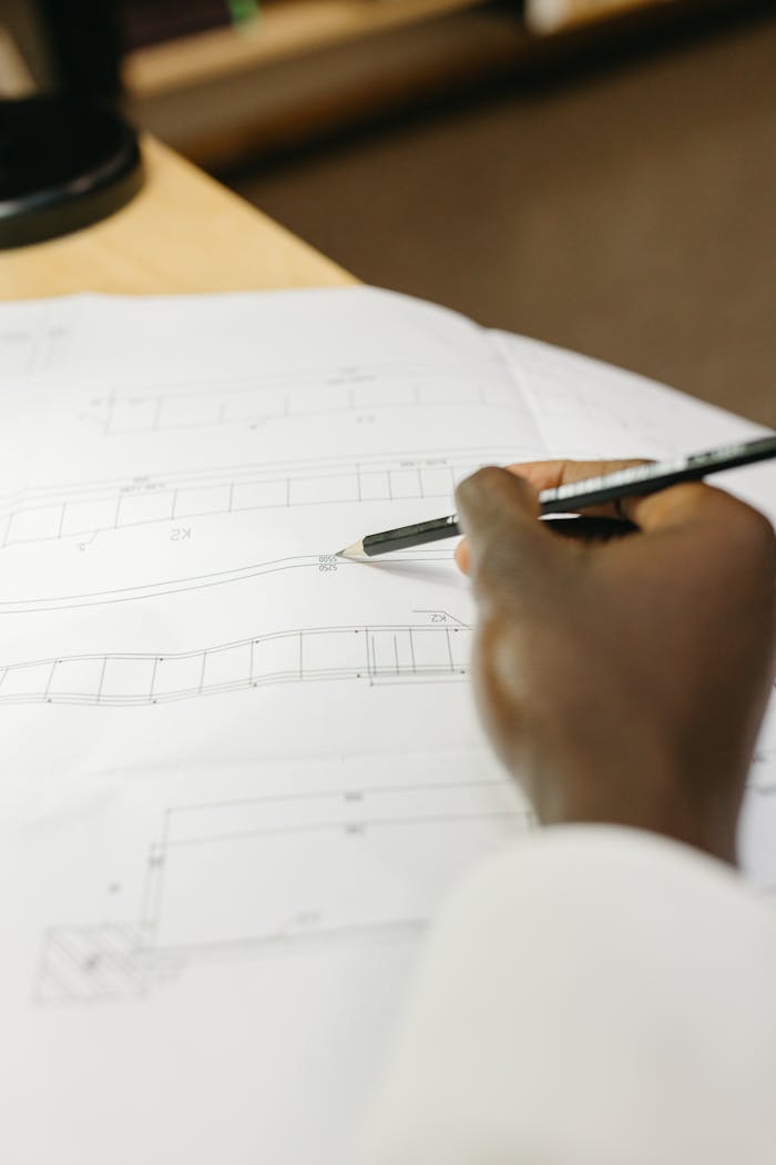 Detailed view of an architects hand drafting a blueprint in a workspace setting.